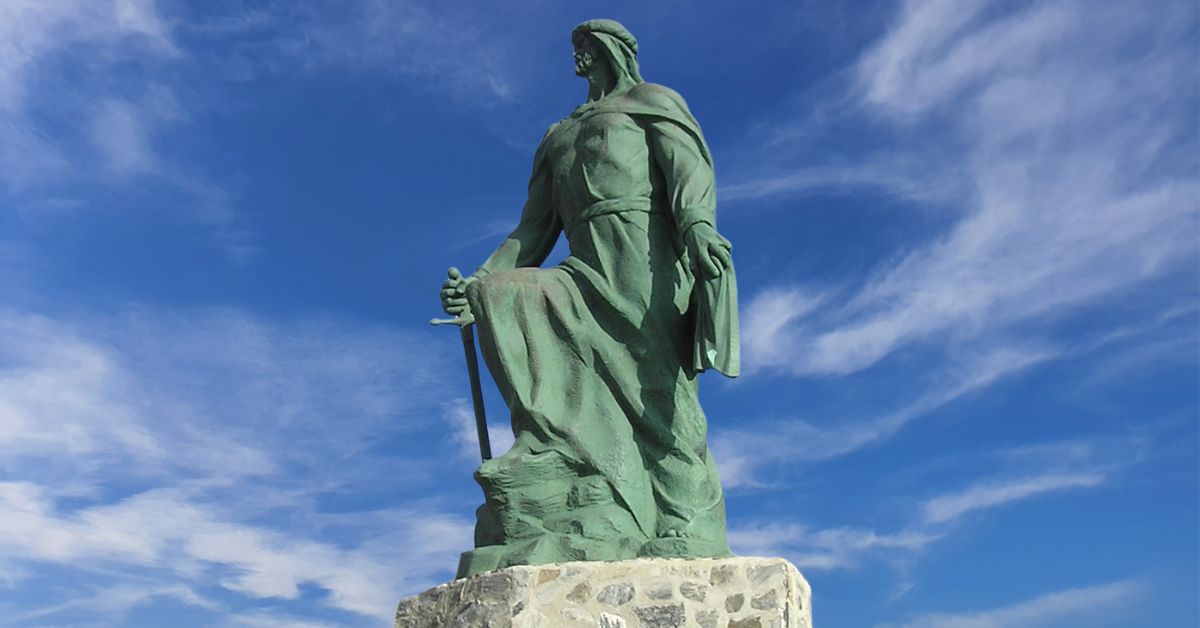estatua de bronde de Abderramán I y el cielo azul con ligeras nueves en el fondo de la imagen
